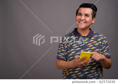 Young multi-ethnic man against gray background 62572030