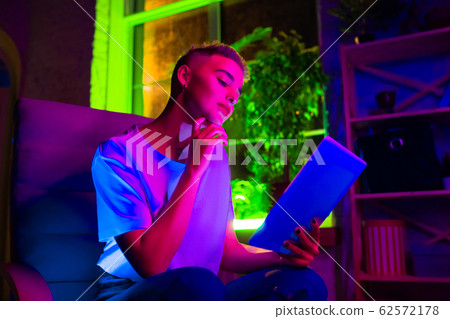 Cinematic portrait of handsome young woman in neon lighted interior 62572178