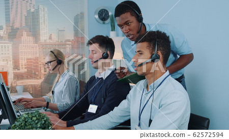 Black manager operator helping his colleague in call center Black manager operator helping his colleague in call center 62572594