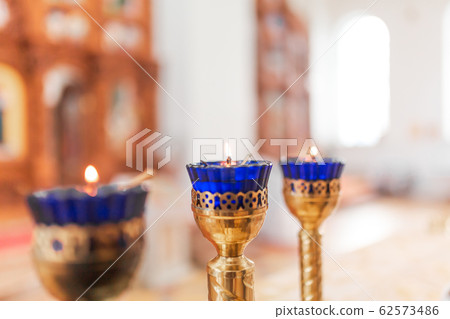 Orthodox Church Lamps with lit candles in blue Orthodox Church Lamps with lit candles in blue 62573486
