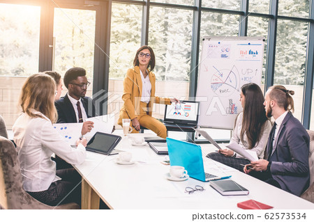 Businesswoman Stands To Address Meeting Around Board Table Businesswoman Stands To Address Meeting Around Board Table 62573534