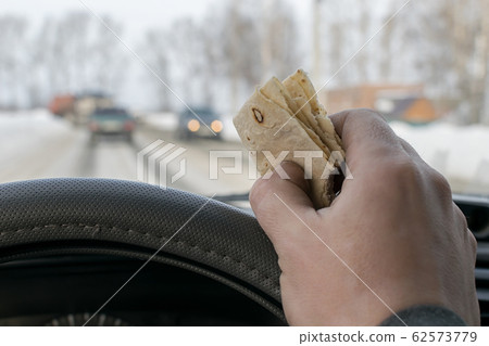 piece of bread cake in the hand of a car driver piece of bread cake in the hand of a car driver 62573779