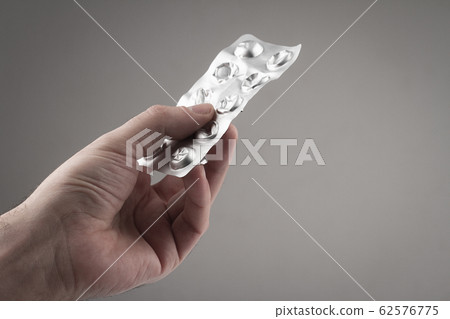 closeup of Caucasian male hand holding pills 62576775