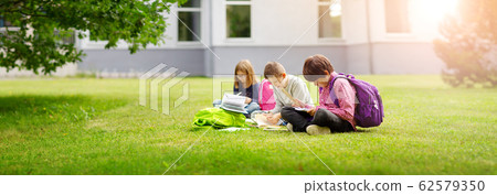 Children with rucksacks standing in the park near school 62579350