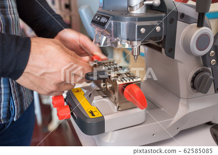 Locksmith in workshop makes new key. Professional 62585085