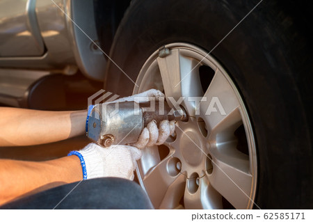serviceman removing bolt from a wheel using serviceman removing bolt from a wheel using 62585171