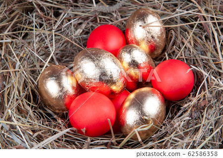 Golden and red eggs in a nest top view. Concept easter. Golden and red eggs in a nest top view. Concept easter. 62586358