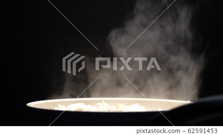 Frying pan with white thick steam in restaurant kitchen on a black background. Cooking chicken meat Frying pan with white thick steam in restaurant kitchen on a black background. Cooking chicken meat 62591453
