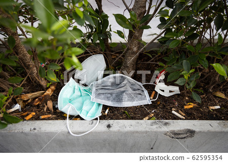 People littering of garbage of used medical masks throw in the crevices of the bushes,hazardous waste,risk of disease,spread of germ,Coronavirus,Influenza virus,concept of throw trash in a trash can 62595354