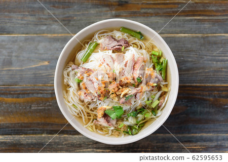 Rice noodles soup with beef in a bowl on wooden background, Top view 62595653