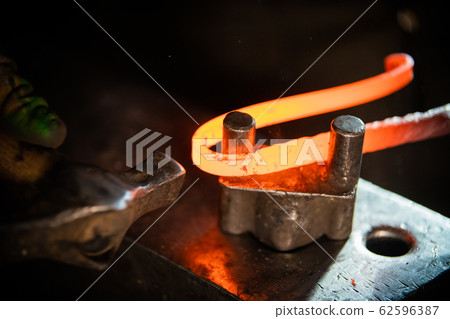 A blacksmith making a unique handle for the knife - bending the metal 62596387