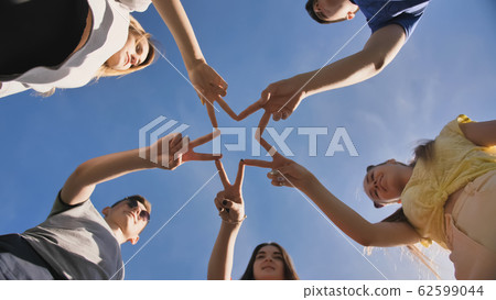 Friends make a star shape from their hands against a blue sky Friends make a star shape from their hands against a blue sky 62599044