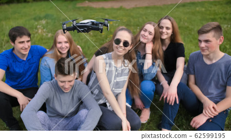 Cheerful friends are watching the flight of the drone. 62599195