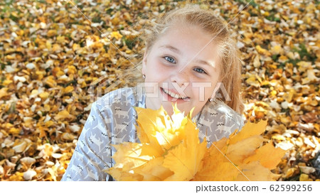 Smiling teen girl posing with autumn leaves. Smiling teen girl posing with autumn leaves. 62599256