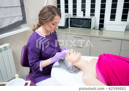 Relaxed woman with a deep cleansing nourishing face mask applied to her face. Spa treatment 62599882