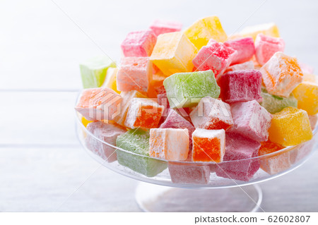 Assortment of Turkish delights on a glass stand. White wooden background. Close up. 62602807