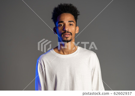 Handsome african american man with trendy curly hairdo on grey studio background. Cheerful guy smiling and looking to camera Handsome african american man with trendy curly hairdo on grey studio background. Cheerful guy smiling and looking to camera 62602937