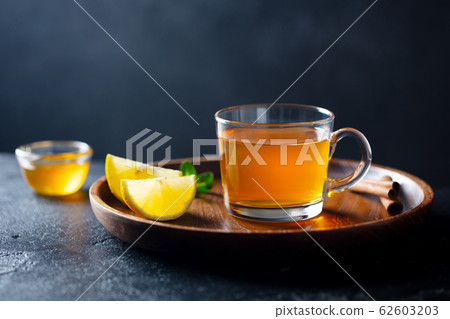 Tea cup with honey and lemon on wooden tray. Grey background. Copy space. 62603203