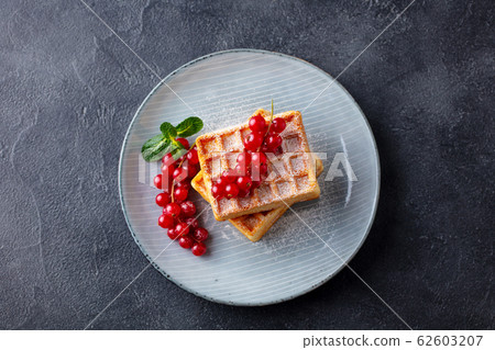 Belgian waffles with fresh red currant berries. Grey dark background. Top view. 62603207