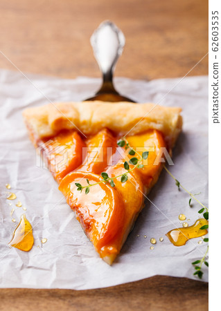 Peach galette, pie, cake on a parchment paper. Wooden background. Close up. Peach galette, pie, cake on a parchment paper. Wooden background. Close up. 62603535