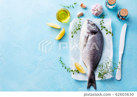 Raw Dorado fish with cooking ingradients. Blue stone background. Top view. Copy space. 62603630