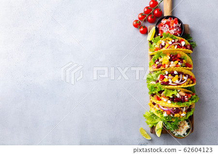 Taco with mixed vegetables, beans on cutting board. Grey background. Copy space. Top view. Taco with mixed vegetables, beans on cutting board. Grey background. Copy space. Top view. 62604123
