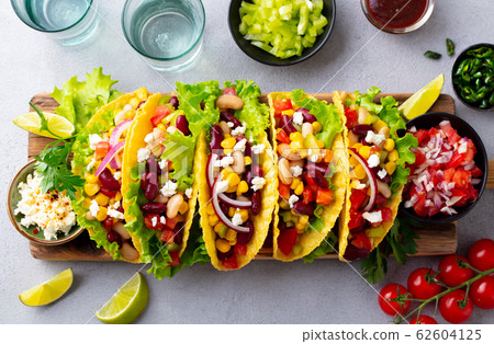 Taco with mixed vegetables, beans on cutting board. Grey background. Top view. Taco with mixed vegetables, beans on cutting board. Grey background. Top view. 62604125