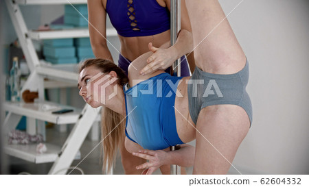 Young attractive plastic woman standing in leg split holding on the pole 62604332