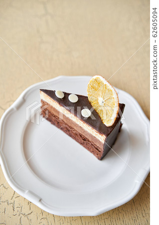 Chocolate sponge cake, with mousse, decorated with Orange slice and meringue. Breakfast in the cafe, morning coffee. on wooden table. 62605094