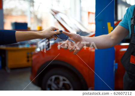 Female driver gives keys to worker in uniform Female driver gives keys to worker in uniform 62607212