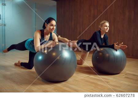 Two slim women, pilates training on balls in gym Two slim women, pilates training on balls in gym 62607278