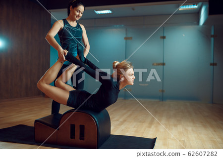 Slim girl with instructor, pilates training in gym 62607282