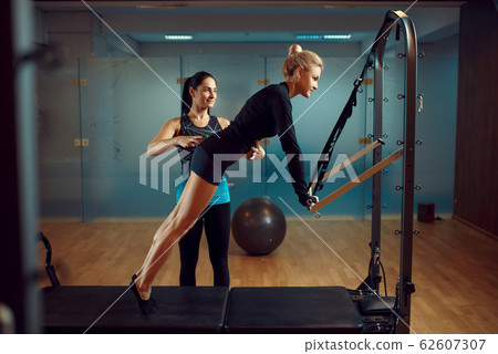 Slim woman and instructor, pilates training Slim woman and instructor, pilates training 62607307