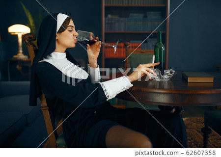 Sexy nun with cigarete and glass of wine 62607358