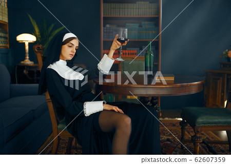 Sexy nun with cigarete and glass of wine 62607359