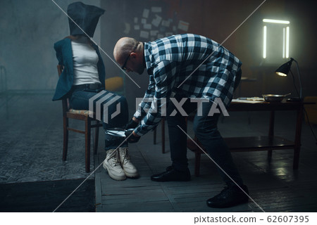 Maniac kidnapper taping his female victim's legs Maniac kidnapper taping his female victim's legs 62607395