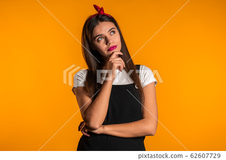 Thinking woman looking up on yellow background. Worried contemplative face expressions. Pretty girl model with cute appearance. Thinking woman looking up on yellow background. Worried contemplative face expressions. Pretty girl model with cute appearance. 62607729
