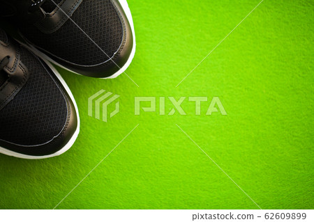 Pair of new stylish sneakers on green background. 62609899