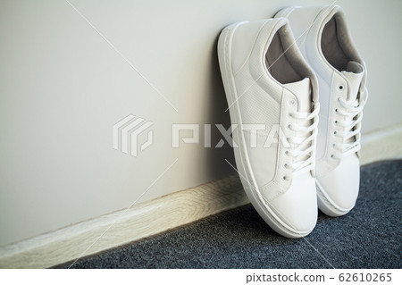 Pair of new stylish white sneakers on floor at home. Pair of new stylish white sneakers on floor at home. 62610265