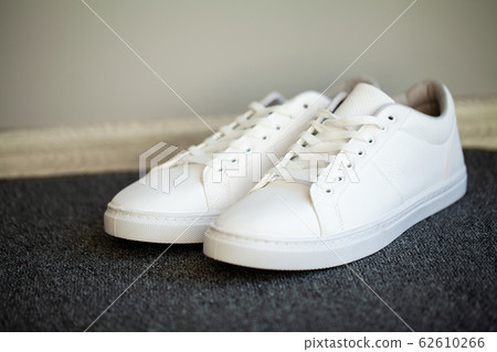 Pair of new stylish white sneakers on floor at home. 62610266