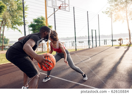 Outdoors Activity. African couple playing basketball on court dribbling in motion happy 62610884