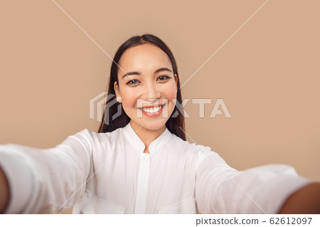 Freestyle. Young woman in shirt standing isolated on bage taking selfie taking selfie on smartphone smiling toothy close-up 62612097