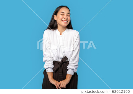 Freestyle. Young woman wearing shirt and skirt standing isolated on blue closed eyes laughing delightful 62612100