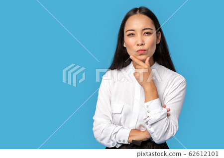 Freestyle. Young woman wearing shirt and skirt standing isolated on blue touching chin thoughtful Freestyle. Young woman wearing shirt and skirt standing isolated on blue touching chin thoughtful 62612101