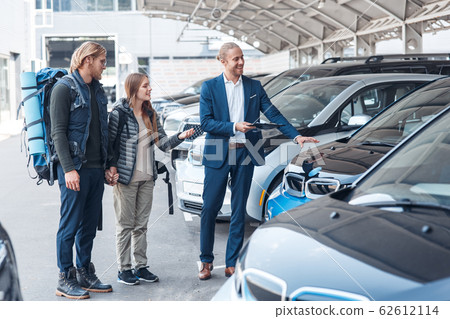 Young adult man and woman choosing rental car for travel Young adult man and woman choosing rental car for travel 62612114