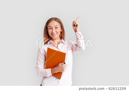 Freestyle. Young businesswoman standing isolated on white with notebook pointing aside smiling excited Freestyle. Young businesswoman standing isolated on white with notebook pointing aside smiling excited 62612209