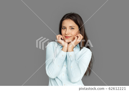 Freestyle. Young woman standing isolated on grey holding face smiling cute 62612221