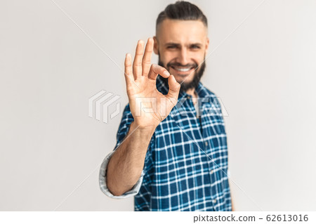 Freestyle. Guy in checkered shirt standing isolated on white showing ok sign close-up blurred background smiling happy 62613016