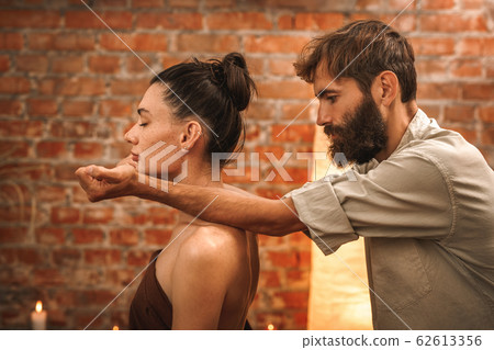 Alternative Medicine. Therapist healing sitting woman in towel smiling relaxed doing massage cracking back leaning on shoulders concentrated 62613356