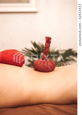 Alternative Medicine. Woman lying on medical bed having churna pinda sweda using herbal powder bolus nude close-up 62613431